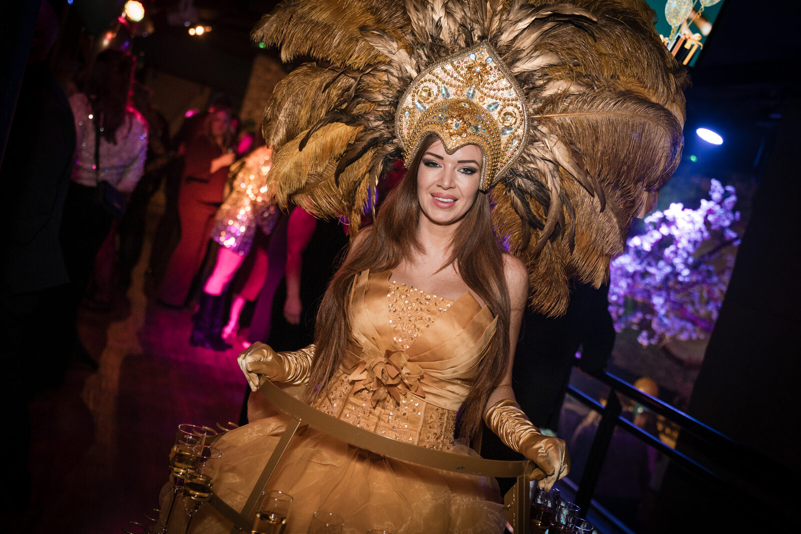 Charmedame met veren-outfit tijdens een bedrijfsfeest bij De Jongens Van
